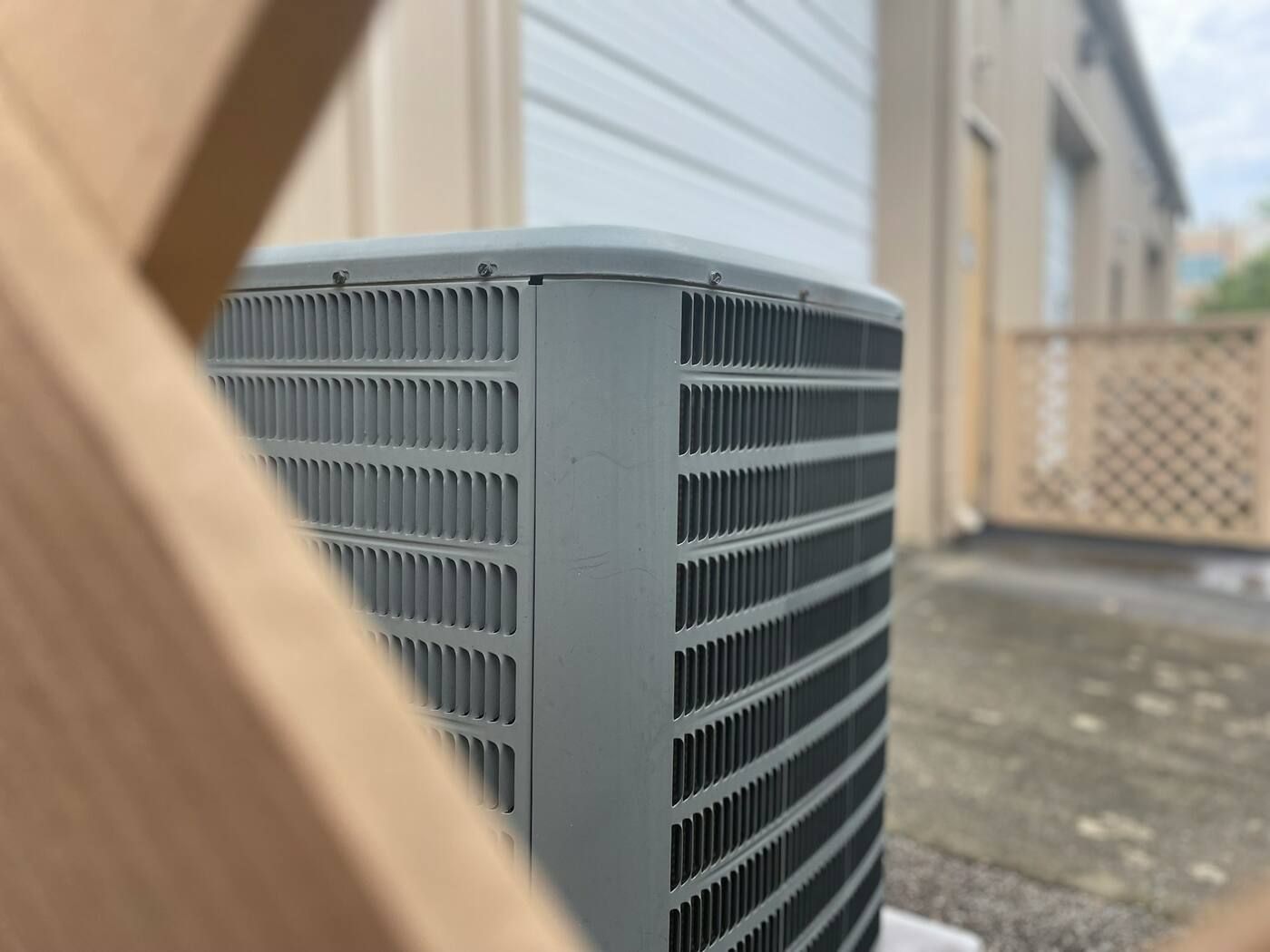 An outdoor AC unit on a pad beside a building with metal siding